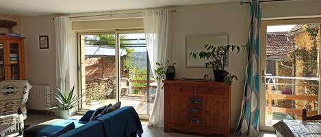 Una habitación con una cama, un armario de madera, una planta en maceta y vistas al exterior.