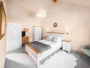 Ein Schlafzimmer mit einem Bett, Nachttischen, einem Kleiderschrank, einem Spiegel und einer Lampe.