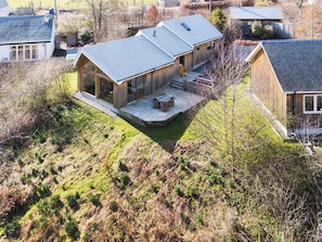 Ein modernes Haus mit einer großen Veranda, einer überdachten Terrasse und Blick auf die umliegende Landschaft.