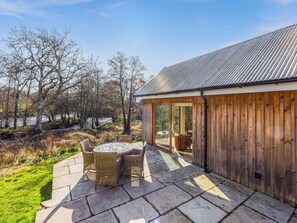 A patio with stone flooring and wicker furniture, a wooden fence, and a view of a natural landscape. - 2 bedroom accommodation in Killin (Killin)