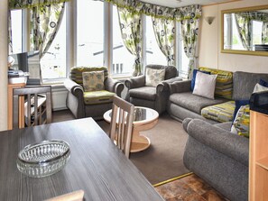 A cozy living room with a sofa, armchair, and a dining table. - 3 bedroom accommodation in Exmouth (Exmouth)