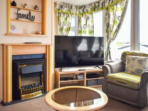A living room with a fireplace, television, and a sofa. - 3 bedroom accommodation in Exmouth (Exmouth)