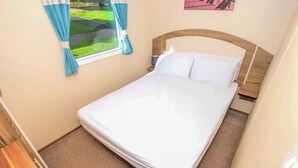 A single bed in a room with a window and a view of a green landscape. - 2 bedroom accommodation in Exmouth (Exmouth)