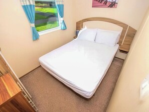 Ein Einzelbett in einem Zimmer mit Fenster und Blick auf eine grüne Landschaft.