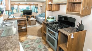 A compact RV kitchen with a stove, sink, and a small dining area. - 2 bedroom accommodation in Exmouth (Exmouth)