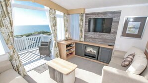 Un balcon avec vue sur la mer, un canapé, une télévision et une cheminée.