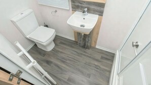 Une salle de bain avec des toilettes, un lavabo et un plancher en bois.