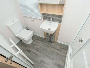 A bathroom with a toilet, sink, and wooden flooring. - 3 bedroom accommodation in Exmouth (Exmouth)