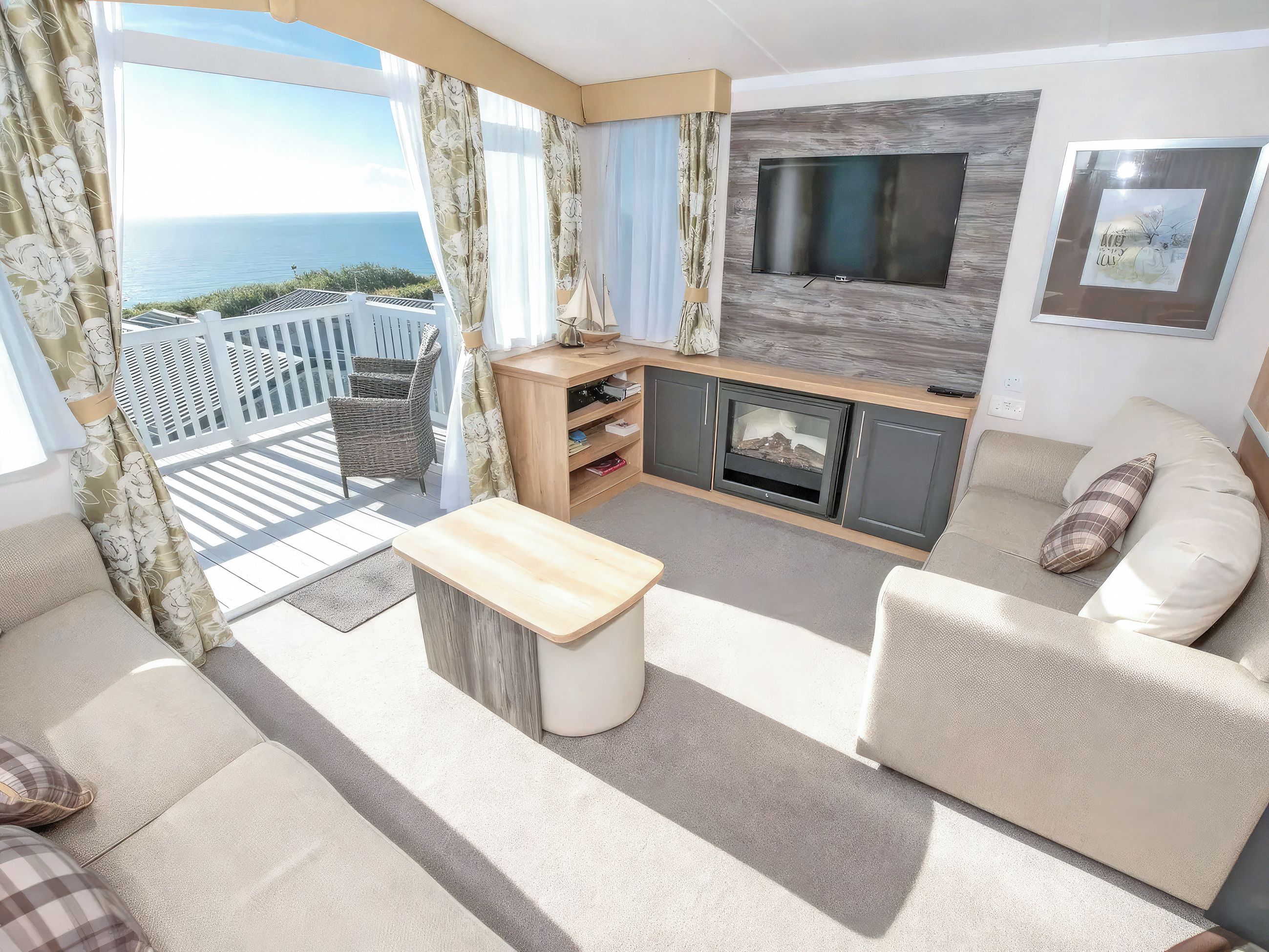 A balcony with a view of the sea, a sofa, a TV, and a fireplace.