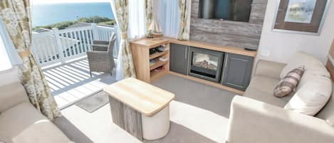 A balcony with a view of the sea, a sofa, a TV, and a fireplace.