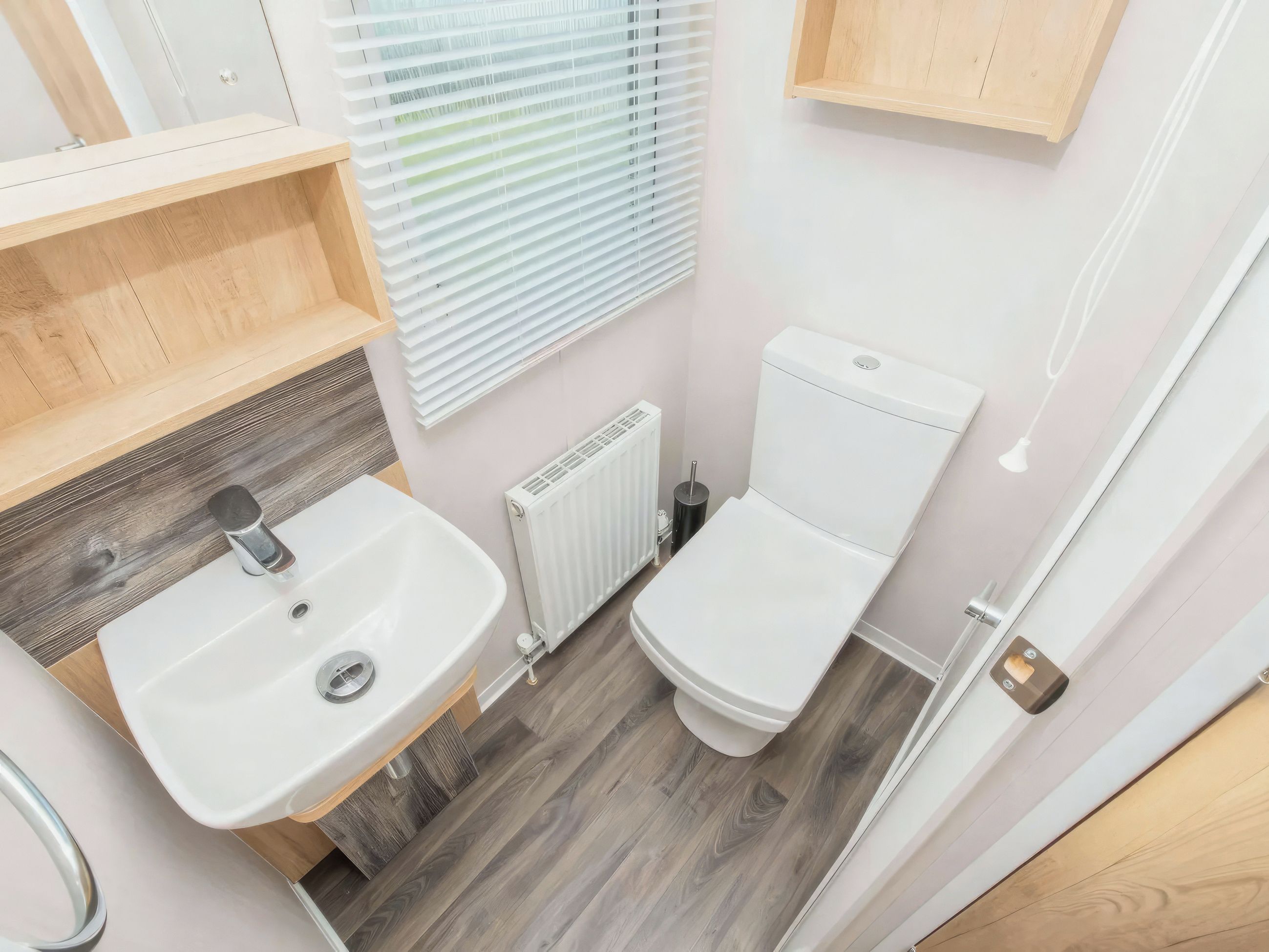A compact bathroom with a white sink, toilet, and radiator.