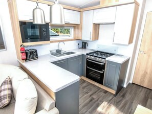 A compact kitchen with a microwave, toaster, sink, stove, and oven. - 3 bedroom accommodation in Exmouth (Exmouth)