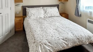 Ein Schlafzimmer mit Bett, Holzschränken, einem Nachttisch und einem Fenster mit Vorhängen.