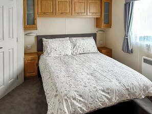 Ein Schlafzimmer mit Bett, Holzschränken, einem Nachttisch und einem Fenster mit Vorhängen.