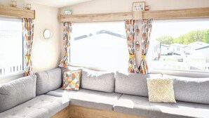 A cozy seating area with a sofa, cushions, and a wooden bench. - Juniper Close 52 - UKC9405 (Exmouth)