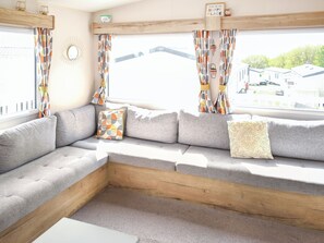 A cozy seating area with a sofa, cushions, and a wooden bench. - Juniper Close 52 - UKC9405 (Exmouth)