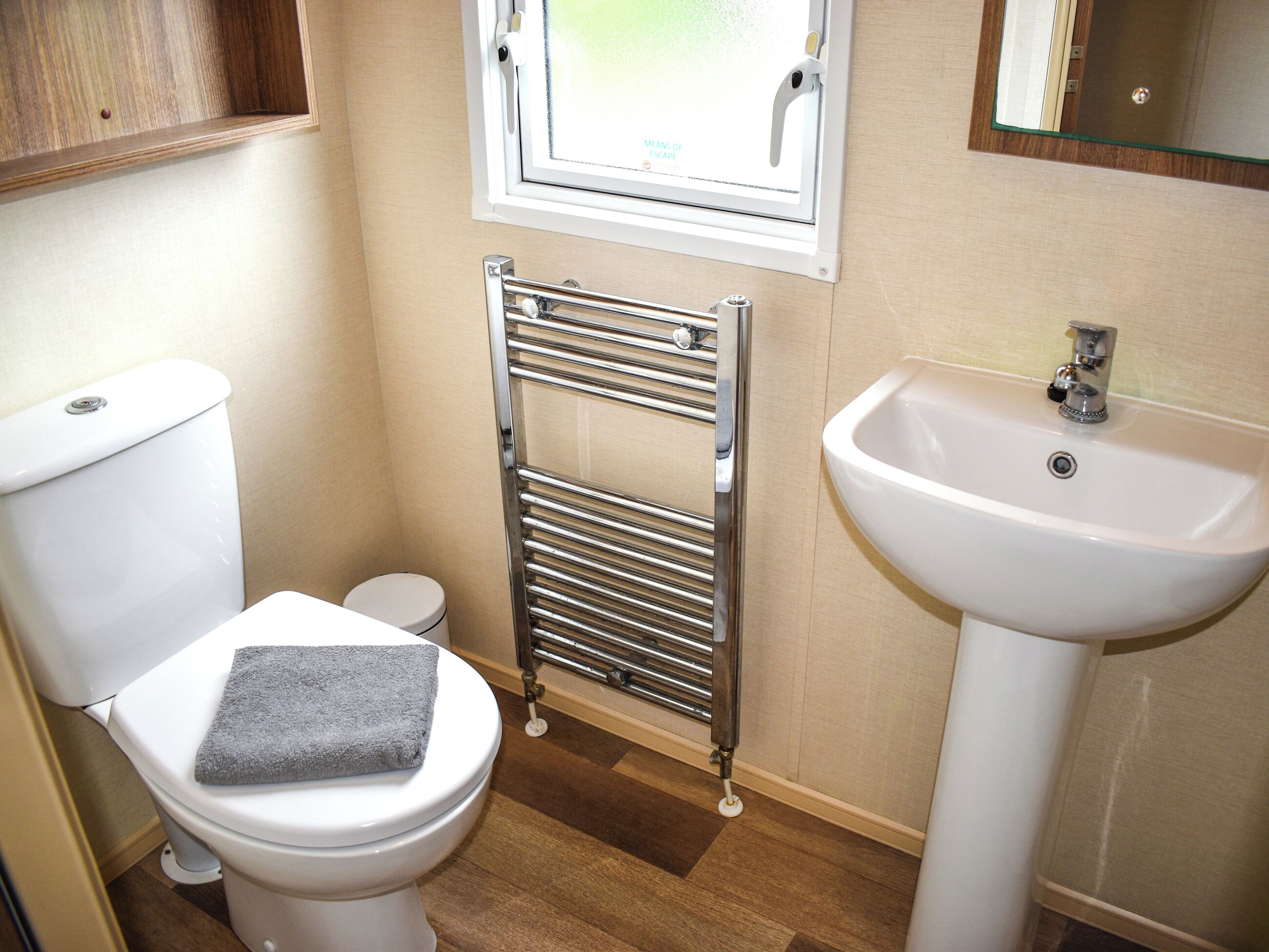 Un baño con inodoro, toalla, radiador y lavabo.