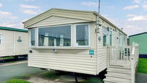A mobile home with a large window, an antenna, and a small porch area.