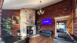 A log cabin interior with a stone fireplace, leather sofas, a mounted television, and wooden walls. - Bellstane Chalet - UKC9440 (Glasgow)