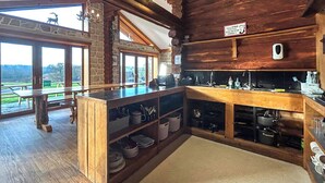A rustic kitchen with wooden beams, a stone wall, and a view of the outdoors. - Bellstane Chalet - UKC9440 (Glasgow)