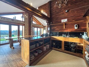 A rustic kitchen with wooden beams, a stone wall, and a view of the outdoors. - Bellstane Chalet - UKC9440 (Glasgow)
