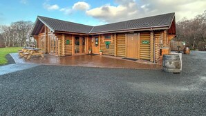 A log cabin-style building with a covered patio and picnic tables. - Bellstane Chalet - UKC9440 (Glasgow)