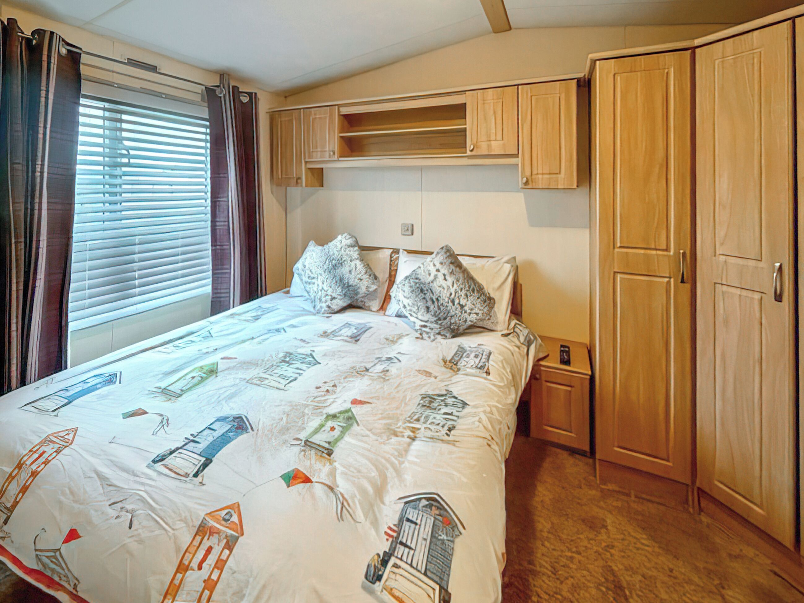 A bedroom with a bed, a nightstand, a wardrobe, and a window with curtains.