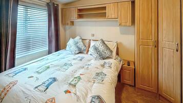 A bedroom with a bed, a nightstand, a wardrobe, and a window with curtains.