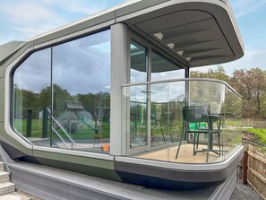 A modern, enclosed outdoor space with large windows, a seating area, and a view of a garden. - 1 bedroom accommodation in Glasgow (Glasgow)