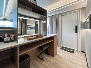 A modern hotel room with a wooden desk, a mirror, a small seating area, and a door. - 1 bedroom accommodation in Glasgow (Glasgow)