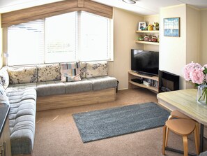 Ein Wohnzimmer mit einer Couch, einem Fernseher, Holzregalen und einem Fenster mit Jalousien.