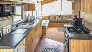Une cuisine compacte pour camping-car, équipée d’une cuisinière, d’un évier et d’un four à micro-ondes.