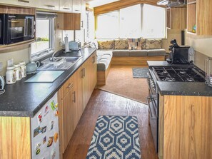 Eine kleine Küchenzeile für ein Wohnmobil, mit Herd, Spüle und Mikrowelle.