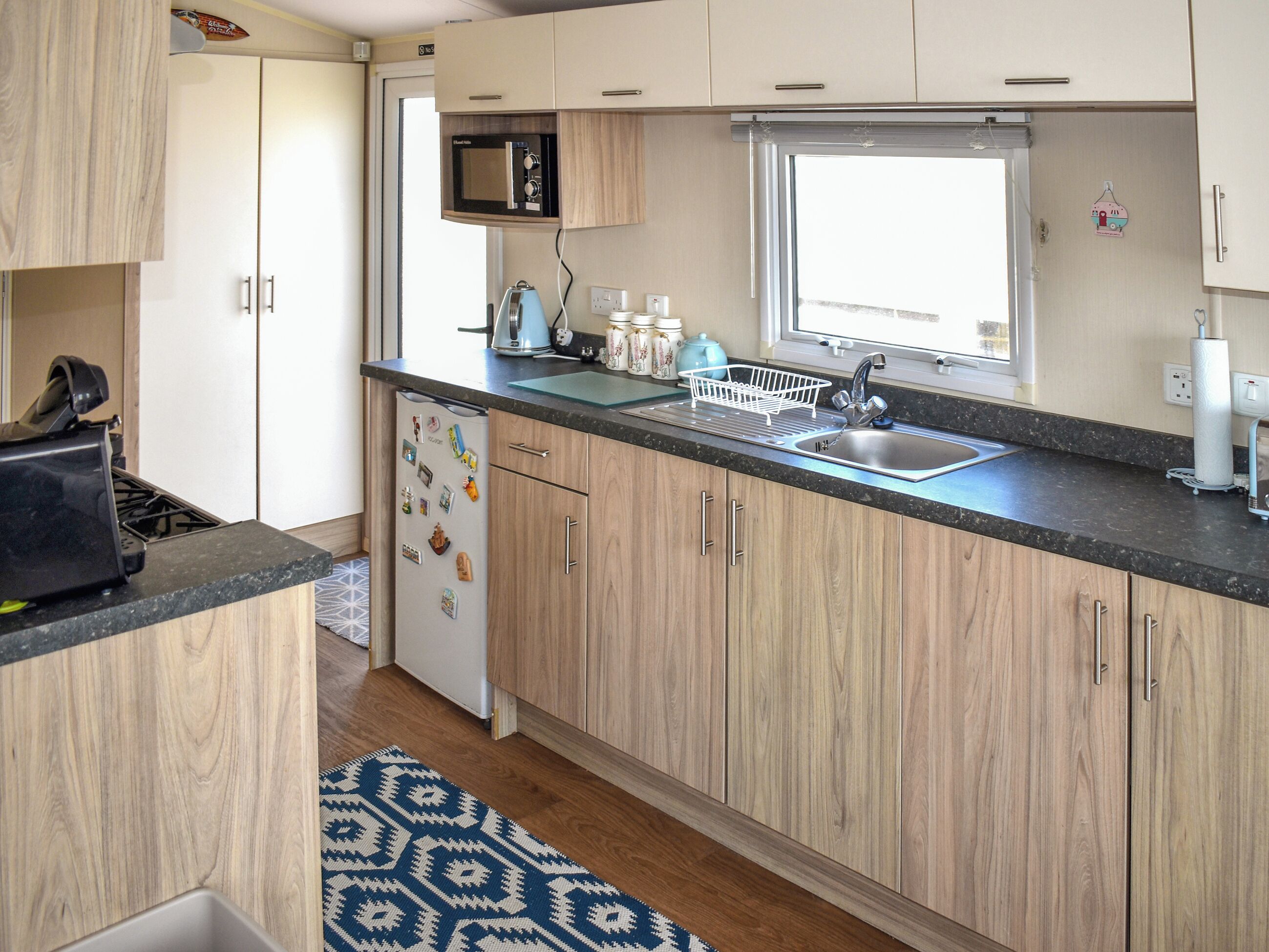A compact kitchen with a microwave, sink, and a window.