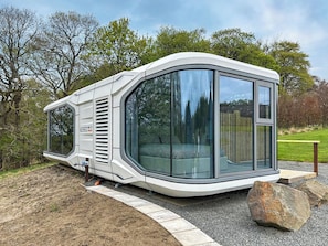 Ein modernes Wohnmobil mit geschwungenem Design, großen Fenstern und einem sichtbaren Schlafbereich.