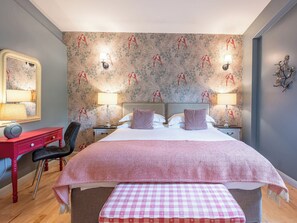 A hotel room with a large bed, two bedside tables with lamps, a red dresser, a chair, and a mirror. - 3 bedroom accommodation in Richmond (Richmond)