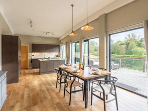 A modern kitchen with a central island, large windows, and a dining area with a view of a lake. - 3 bedroom accommodation in Richmond (Richmond)