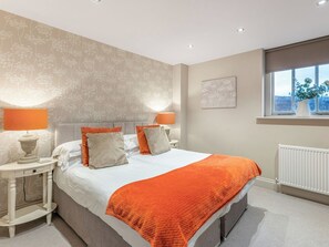 A bedroom with a bed, two bedside tables, a window with a view, and a radiator. - 3 bedroom accommodation in Richmond (Richmond)
