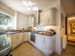 A modern kitchen with white cabinets, a granite countertop, and a built-in oven.