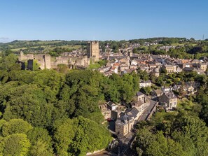 Eine historische Stadt mit einem markanten Schloss, umgeben von dichtem Grün und Wohngebäuden.