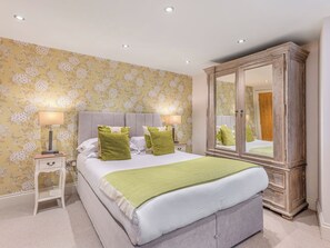 A bedroom with a bed, two bedside tables, a mirror, and a wardrobe.