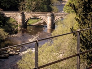 A stone bridge over a river with trees and a railing in the foreground. - 2 bedroom accommodation in Richmond (Richmond)