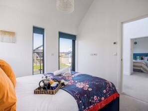 Ein Schlafzimmer mit einem großen Bett, einem Fenster und einer Tür zu einem anderen Raum.