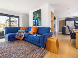 A modern living room with a blue sofa, a colorful rug, and a wooden coffee table. - 3 bedroom accommodation in Dorchester (Dorchester)