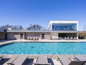 Ein modernes Gebäude mit Pool, Liegestühlen und blauem Himmel.
