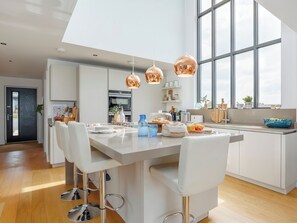 Eine moderne Küche mit einer zentralen Kochinsel, Pendelleuchten und einem großen Fenster.