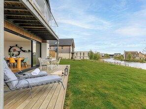 Ett modernt hus med en terrass, en matplats och utsikt över en flod.
