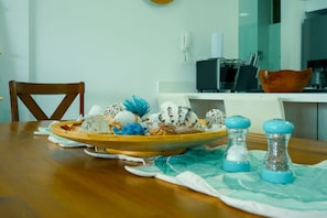 A dining table with a plate of decorative shells, salt and pepper shakers, and a placemat. - Luxury Resort Condo in Santa Marta Walk to Beach (Santa Marta)