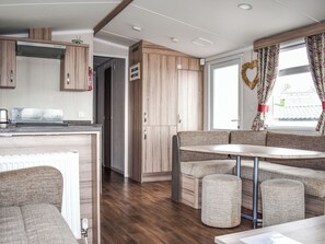 Ein kompaktes Wohnmobil-Interieur mit einer Küchenzeile, einer Sitzecke und einem Fenster mit Vorhängen.
