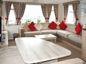 Ein gemütliches Zimmer mit einer Couch, einem Couchtisch und Vorhängen.